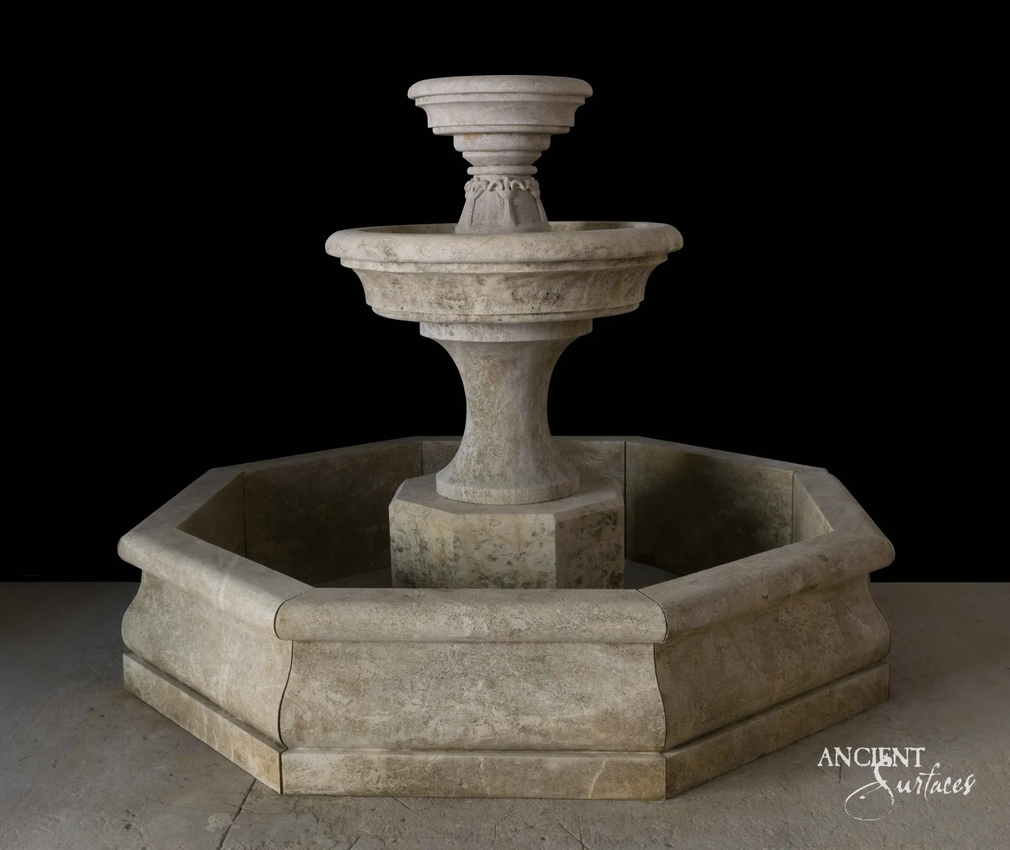 Reclaimed antique limestone two tier bowl fountain from Ancient Surfaces on a turned baluster shaft, standing at the centre of an octagonal basin, photographed against black