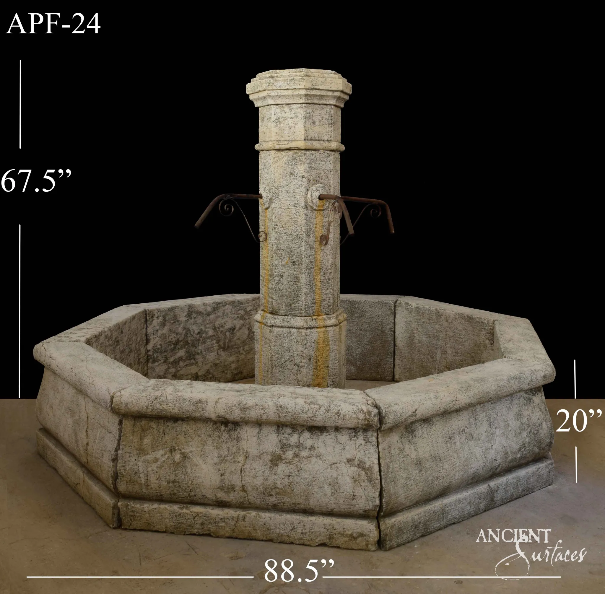 Reclaimed antique limestone octagonal pedestal fountain from Ancient Surfaces, catalogued as APF 24, with twin scrolled iron spouts, photographed against black with dealer measurements of 88.5 inches wide and 67.5 inches high