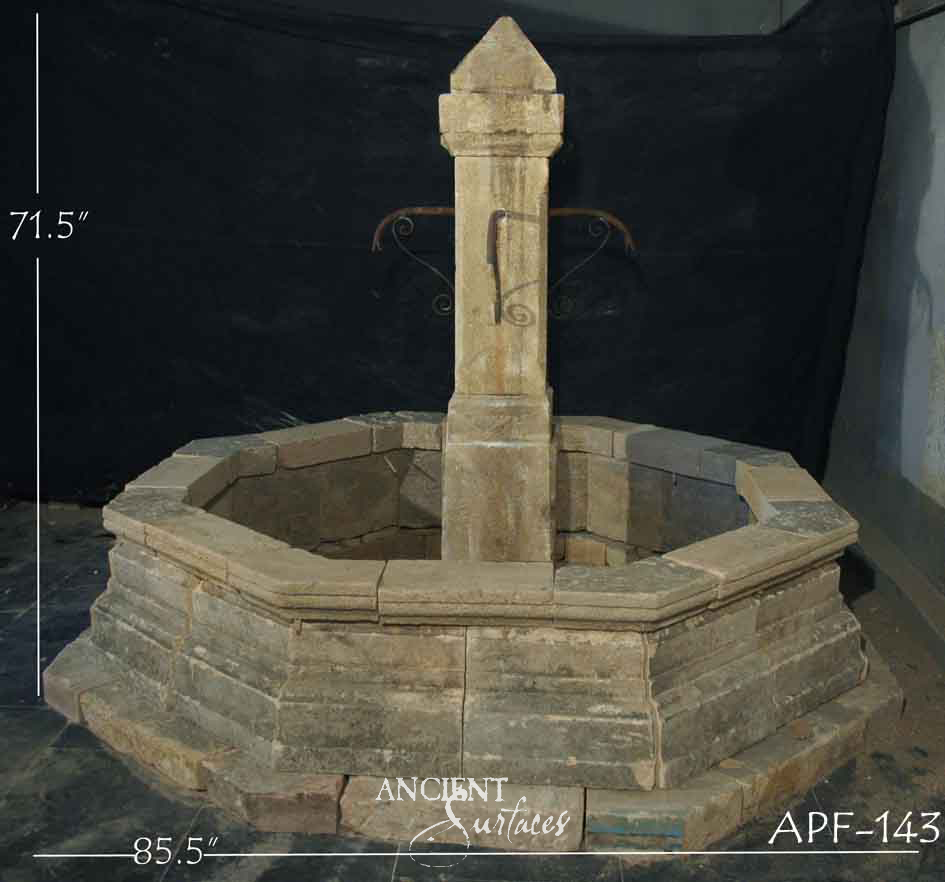 Reclaimed antique limestone octagonal basin fountain from Ancient Surfaces, catalogued as APF 143, built from dry stacked stone courses with a pyramid capped pedestal, photographed against black with dealer measurements of 85.5 inches wide